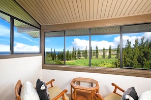Un balcon donnant sur un terrain de golf, avec des chaises en bois et une table hexagonale.