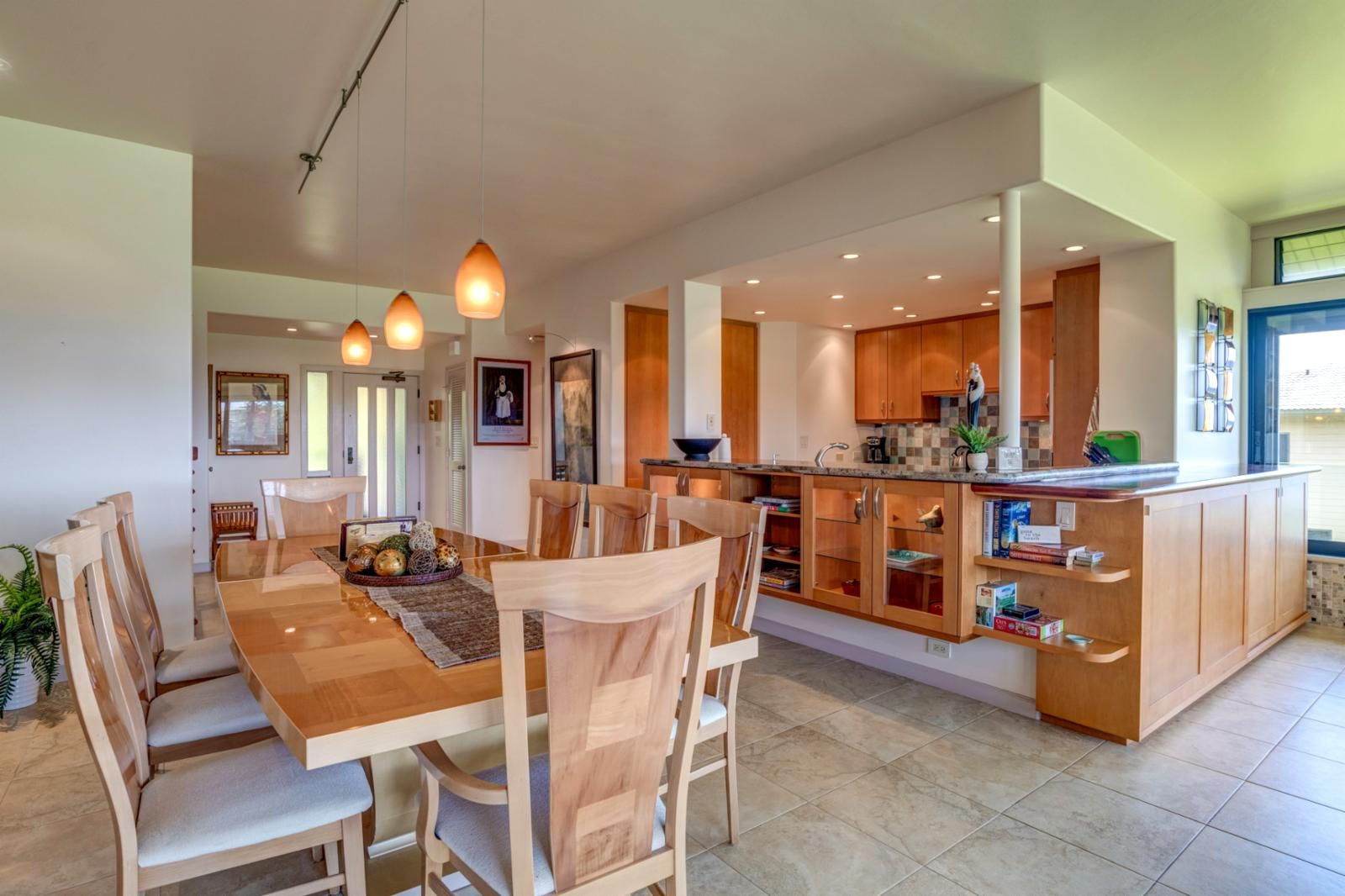 A modern kitchen with wooden cabinets, a central island, and pendant lighting.
