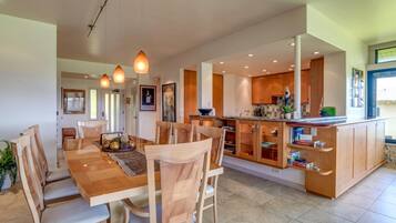 A modern kitchen with wooden cabinets, a central island, and pendant lighting.