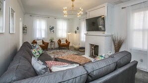 Una sala de estar con un sofá seccional gris, una chimenea, un televisor y una araña.