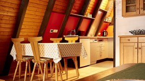A cozy kitchen with wooden beams, a dining table with chairs, and a small cabinet.