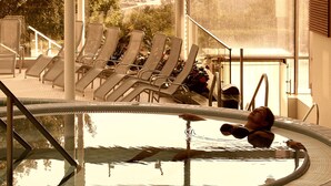 A pool area with lounge chairs and a hot tub.