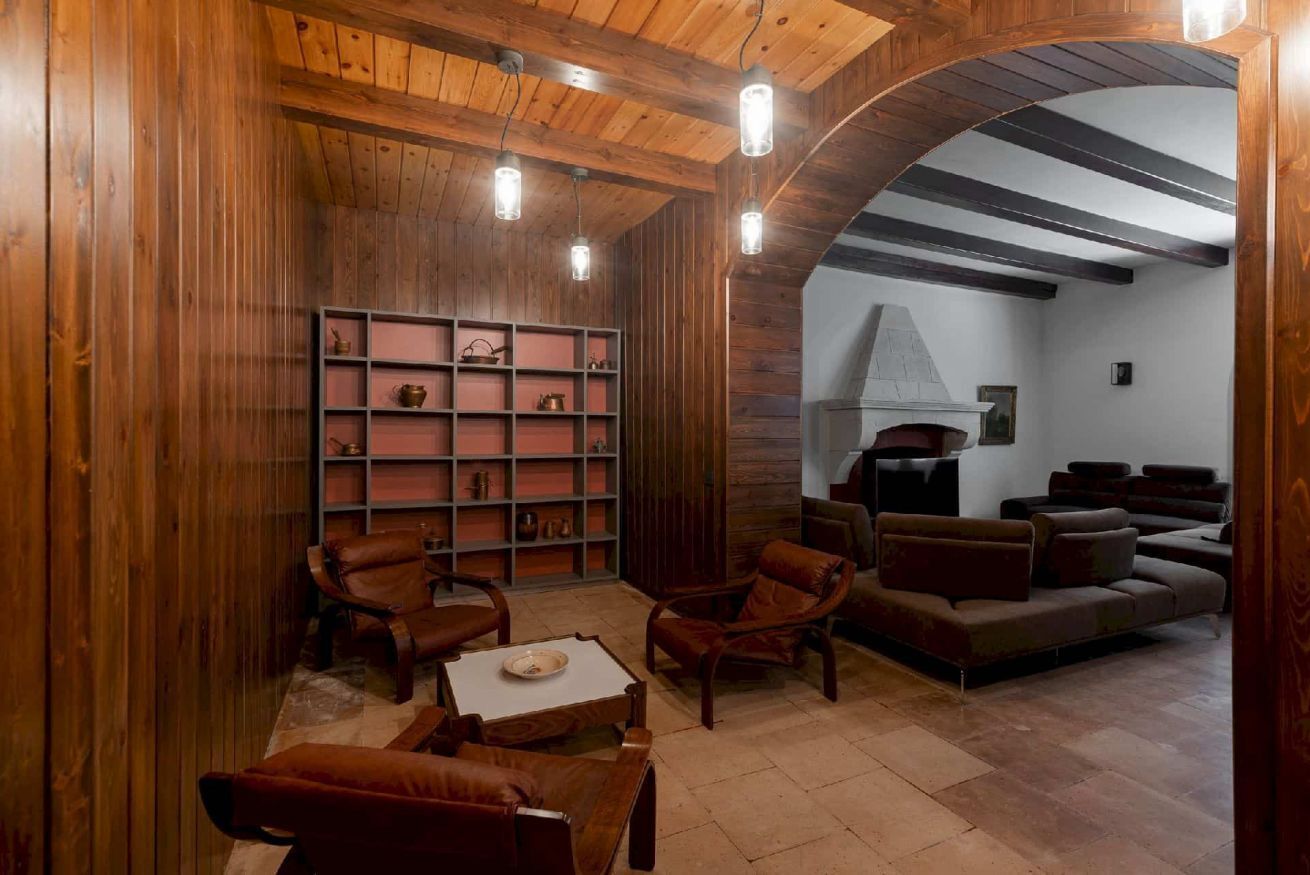 Un interior de madera con chimenea, muebles de cuero y una estantería.