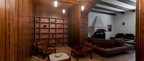 Un interior de madera con chimenea, muebles de cuero y una estantería.
