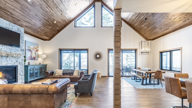 Amplia sala de estar con chimenea, asientos y comedor con luz natural gracias a grandes ventanales.