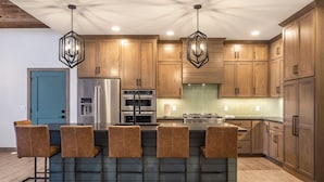 Una cocina moderna con armarios de madera, electrodomésticos de acero inoxidable y una isla central con taburetes de bar.