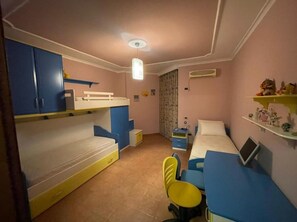 Ein gemütliches Schlafzimmer mit Etagenbetten, einem Schreibtisch, einem Stuhl, einem Bett und einem Regal mit Dekoration.