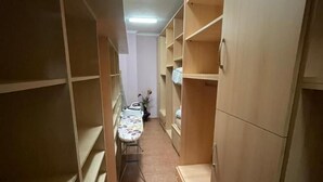 En smal hall med hyllor i trä på båda sidor, ett klinkergolv och en taklampa.