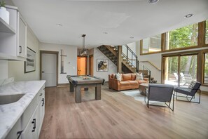 Relax in a spacious living area with a pool table, comfortable sofa, and modern armchair.