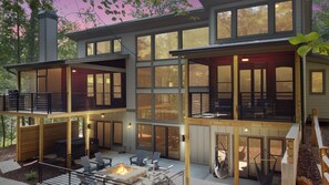 Relax on the spacious outdoor deck with comfortable seating and a fire pit, surrounded by forest views.