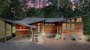 A modern log cabin with a stone foundation, large windows, and a covered porch. - Watersong Falls ~ Private Waterfall, Hot Tub, Fire Pit & More (Ellijay)
