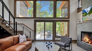 A modern living room with a fireplace, leather sofa, and a coffee table. - Watersong Falls ~ Private Waterfall, Hot Tub, Fire Pit & More (Ellijay)