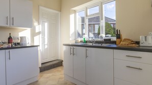 A modern kitchen with white cabinets, a window providing natural light, and a view of the outside.