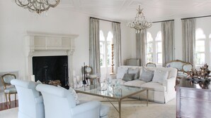 Un salón amplio con chimenea, candelabros elegantes y muebles clásicos.