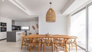 Eine moderne Küche mit Kochinsel, Esstisch aus Holz und Stühlen.