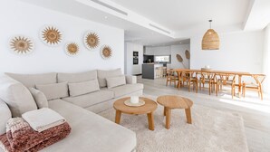 Ein modernes Wohnzimmer mit einer Couch, einem Couchtisch und einem Essbereich mit Holzmöbeln.