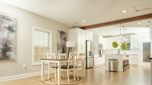 Una cocina moderna con armarios blancos, una isla central y un comedor con una mesa redonda y sillas.
