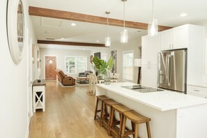 A spacious kitchen with a large island, wooden bar stools, and modern appliances. - Welcome to Beltline (Atlanta)