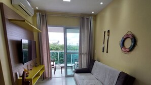 Een moderne woonkamer met een bank, televisie en een balkon met uitzicht.