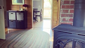 Une pièce avec un plancher en bois, une cheminée noire, un tapis à motifs et un meuble en bois doté de tiroirs.