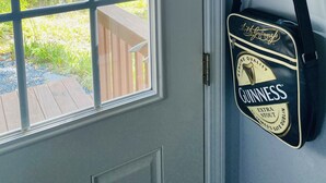 Une porte avec une fenêtre, un sac noir suspendu orné d’une étiquette Guinness, et un rideau blanc.
