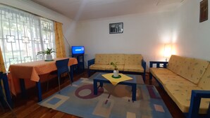 Un soggiorno con divano, tavolino, televisore e zona pranzo con tavolo e sedie.