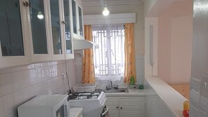 Una cucina compatta con mobili bianchi, un forno a microonde, un piano cottura e un lavandino.