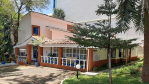 Un edificio a due piani con un balcone, piante in vaso e un prato curato.