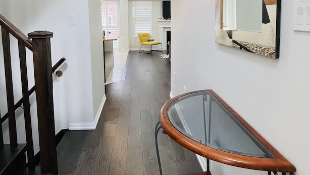 A modern interior with a staircase, a glass table with a brown leather chair, and a decorative mirror on the wall. - Beautiful detached 3 bedroom house,5 min from GO station. (Brampton)