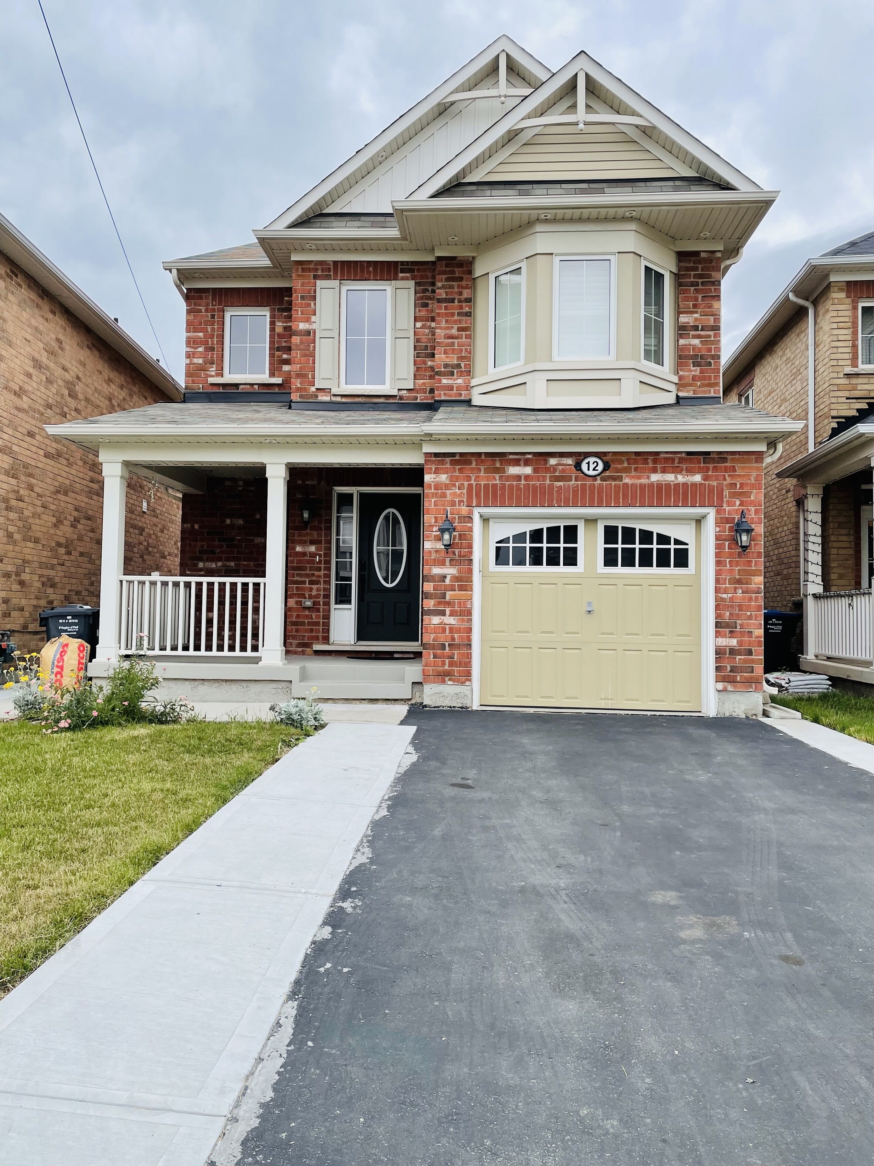 A two-story house with a garage, a front porch, and a brick facade.
