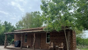 Une cabane rustique dotée d’une véranda, de deux fenêtres et de deux chaises.