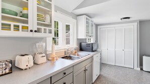 Une cuisine moderne avec des meubles blancs, un four encastré et un micro-ondes.