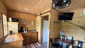 Un intérieur en bois comprenant une cuisine, un coin repas et un téléviseur fixé au mur.