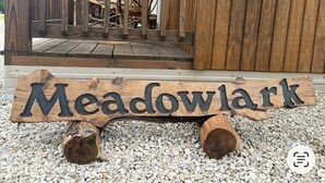 Une enseigne en bois portant le nom « Meadowlark », placée sur un sol recouvert de gravier.
