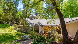 A house with a conservatory, surrounded by a garden with various plants and flowers. - The Eclipse House: Escape to the Trees (Nevada City)