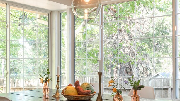 A dining area with a wooden table, white chairs, and a hanging light fixture. - The Eclipse House: Escape to the Trees (Nevada City)