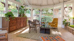 A sunlit conservatory with wooden furniture, a ceiling fan, and potted plants. - The Eclipse House: Escape to the Trees (Nevada City)