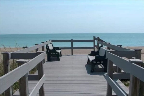Walk along the boardwalk to the serene beach, where two chairs await your arrival.
