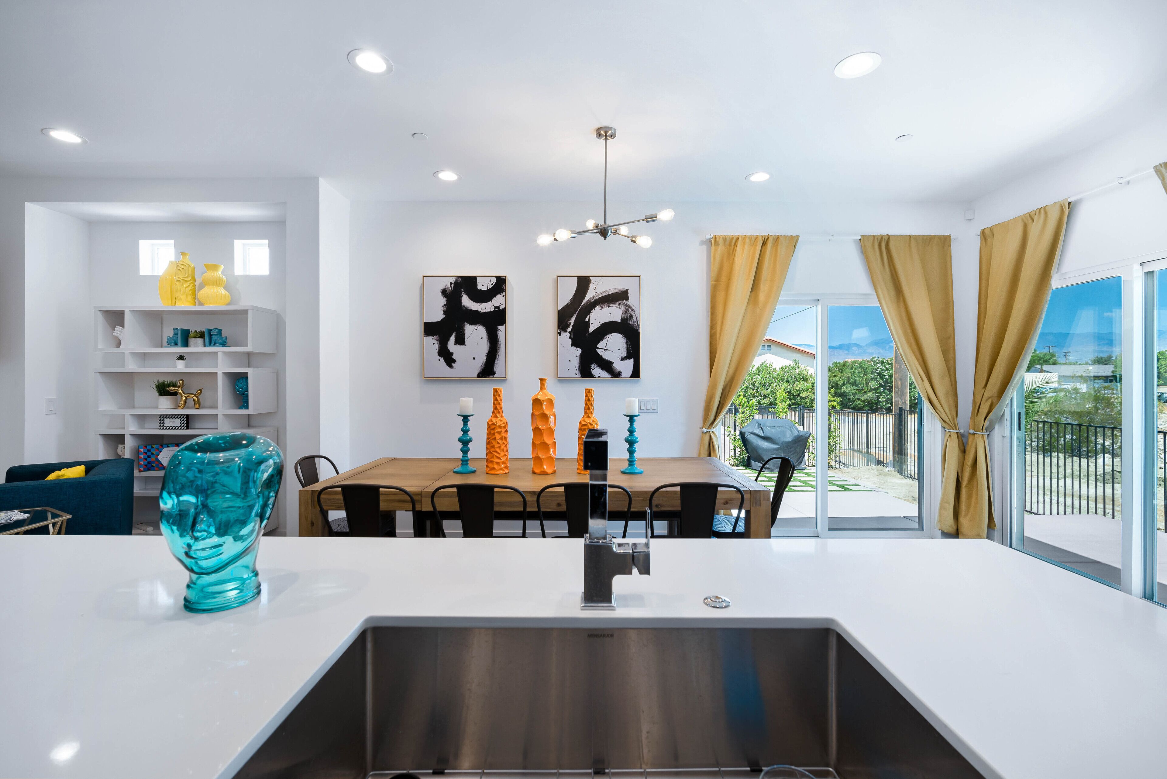 A modern kitchen with a central island, white cabinetry, and a dining area with a wooden table and chairs.