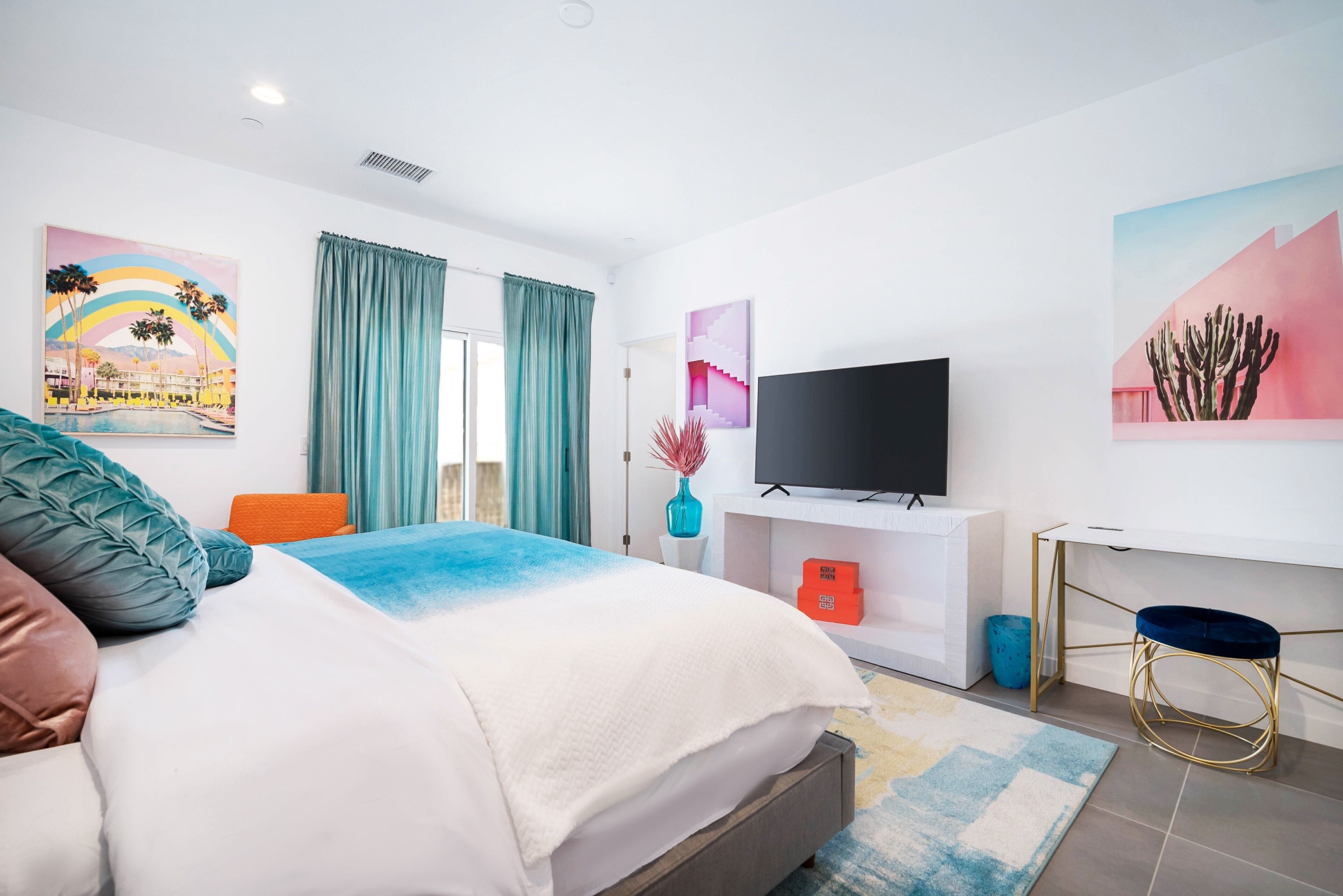 Une chambre d’hôtel moderne, dotée d’un grand lit, d’une télévision et d’œuvres d’art accrochées aux murs.