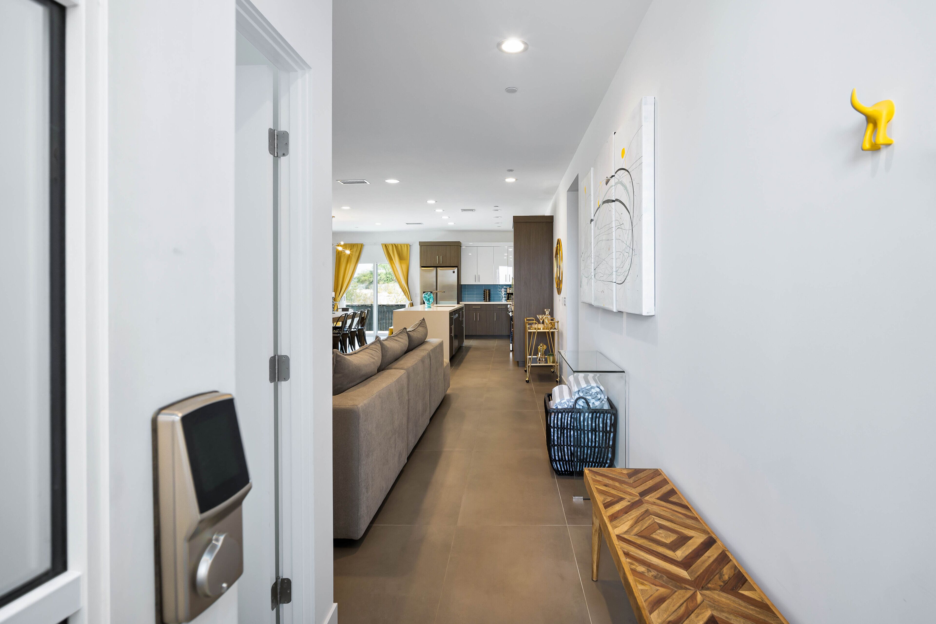 Un intérieur moderne avec un couloir menant à un espace de vie, une cuisine et un coin repas.