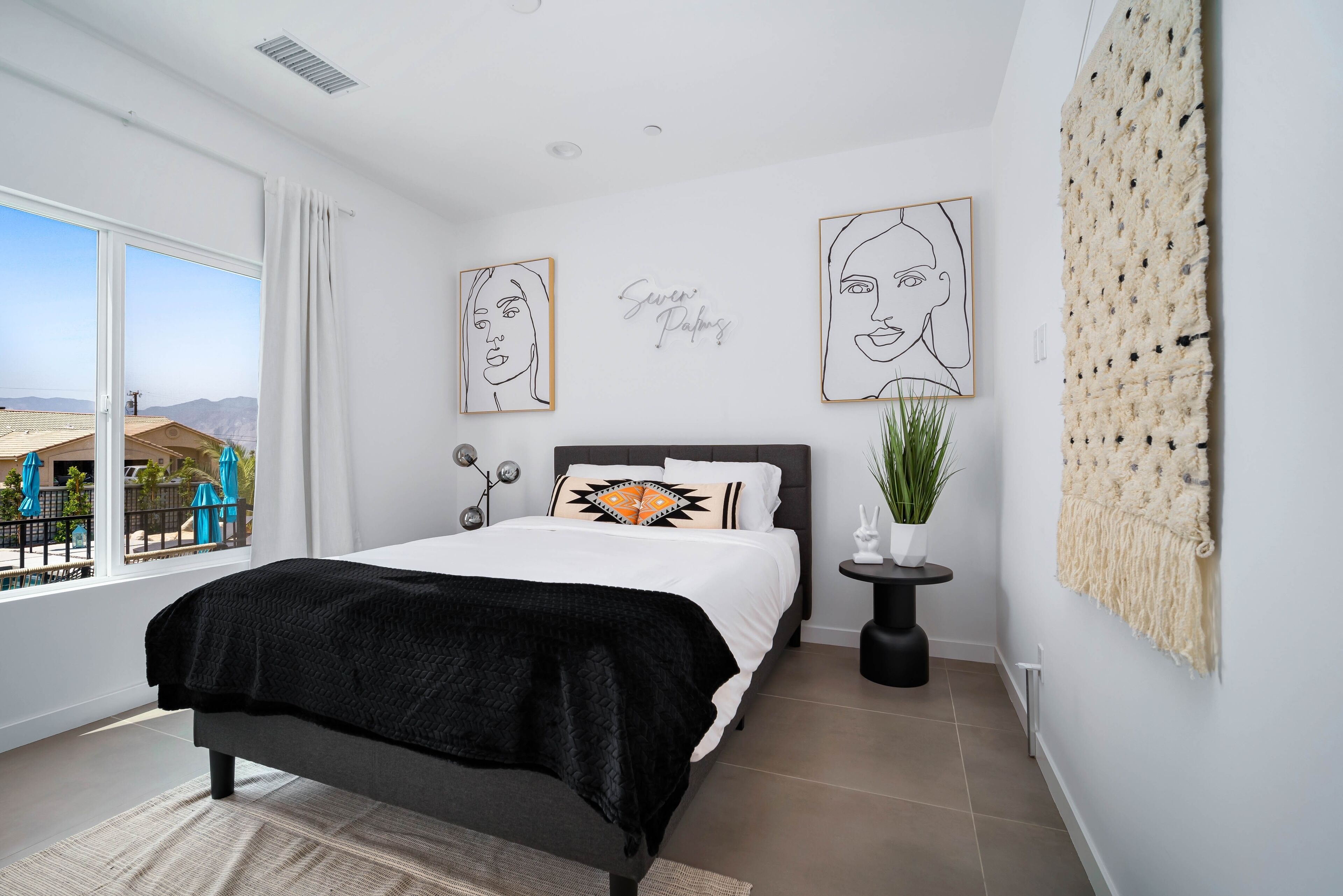 Une chambre moderne avec un grand lit, une vue sur l’extérieur et des œuvres d’art accrochées aux murs.