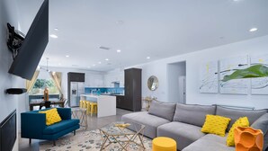 Ein modernes Wohnzimmer mit einer Couch, einem Couchtisch und einem an der Wand montierten Fernseher.