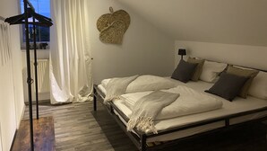 Une chambre à coucher comprenant un lit, une table de chevet, une lampe, une fenêtre avec des rideaux et un décor mural en forme de cœur.