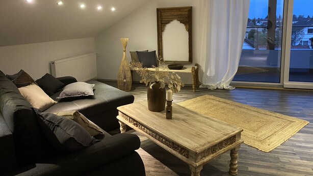 Un salon chaleureux avec un canapé, une table basse et une table d’appoint agrémentée d’objets décoratifs.