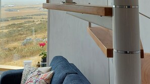 A modern interior with a wooden ceiling, a white pillar, and a blue sofa with patterned cushions. - Geodesic Dome with Stunning Glacier and Mountain views (Puerto Natales)