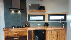 A kitchen with a wooden island, a black dishwasher, a microwave, and a window above the sink. - Geodesic Dome with Stunning Glacier and Mountain views (Puerto Natales)