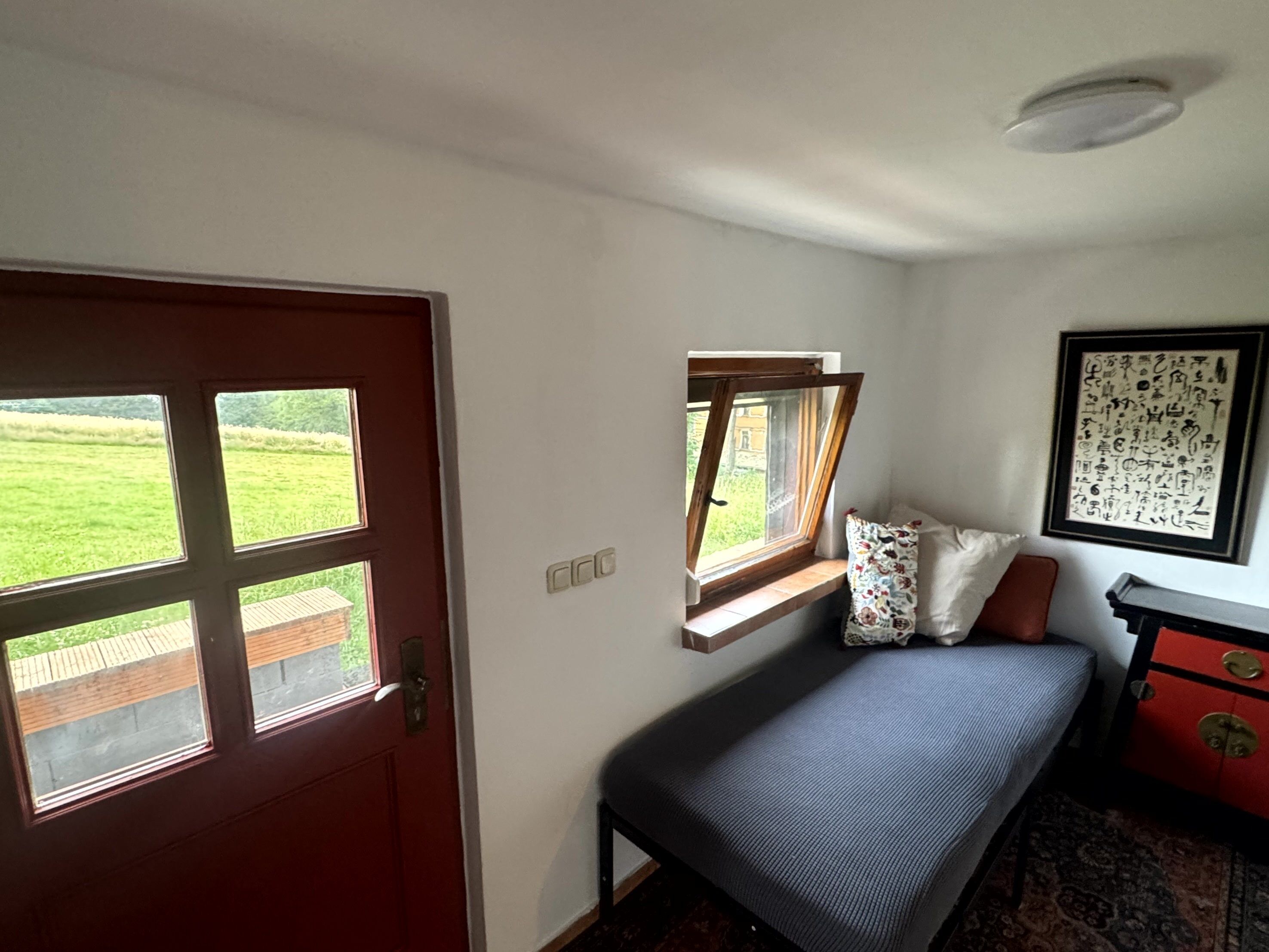 Un dormitorio con cama, ventana, puerta y cómoda.
