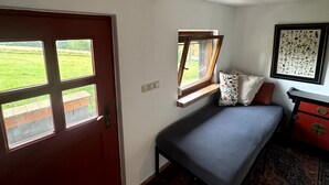 Een slaapkamer met een bed, een raam, een deur en een kapstok.