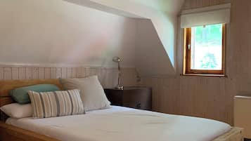 A wooden bed in a room with a sloped ceiling and a window.